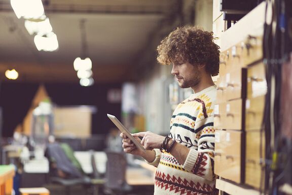 Junger Mann in Werkstatt arbeitet mit Tablet.