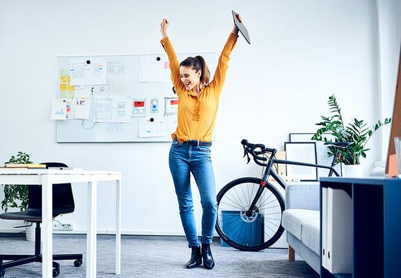 Junge Frau steht jubelnd im Büro