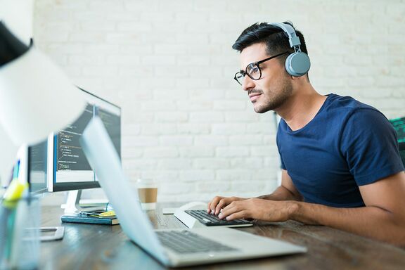 Student mit Kopfhörern sitzt vor einem Laptop 