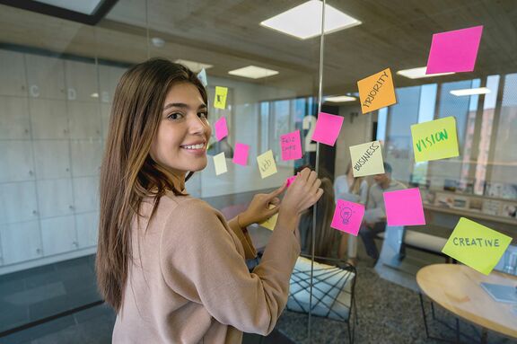 Frau klebt Post its im Büro auf