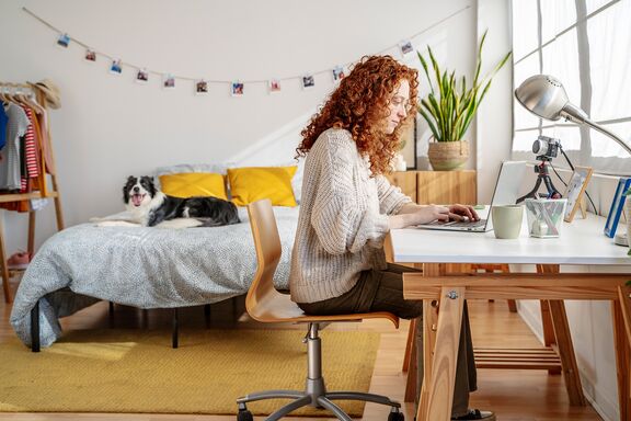 Frau sitzt zuhause am Schreibtisch und lernt für Studium