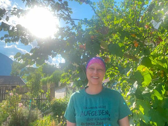 Angelika Kellner steht vor einem Baum und lächelt.