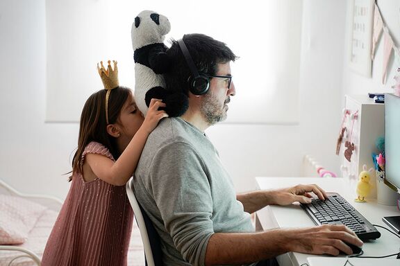 Kind beobachtet Vater wie er am Laptop arbeitet