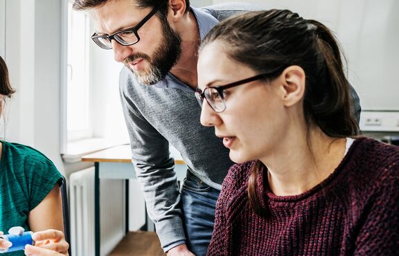 Drei Techniker:innen im Austausch bei der Arbeit