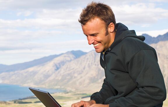 Mann mit Laptop in freier Natur auf Berg