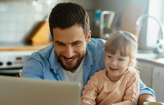 Mann mit Kind an Notebook in der Küche