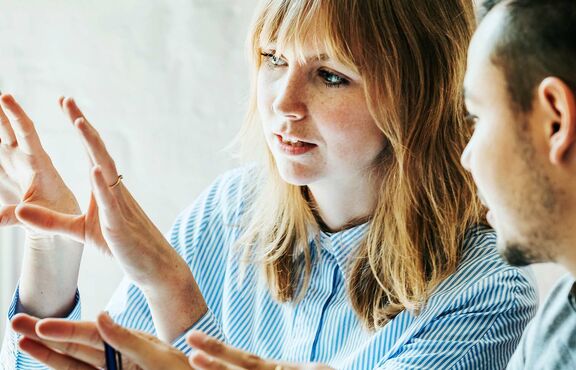 Mitarbeiterin und Studierender tauschen sich im Studienzentrum aus 