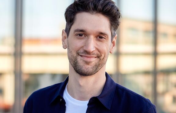 Mann vor gläserner Häuserfassade