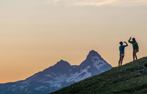 Zwei Menschen klatschen sich auf einem Berggipfel ab