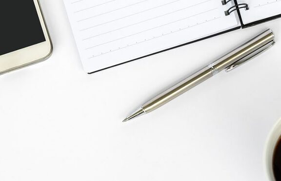 Foto mit Pflanze, Tastatur, Kaffee, Kugelschreiber und Notizblock