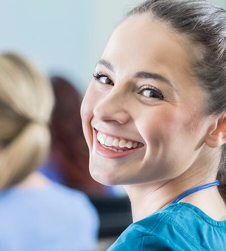 Frau in Pflegekittel lacht in die Kamera