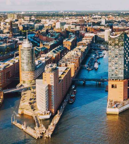 Luftaufnahme von den Hamburger Landungsbrücken, dem Hafen, bei Sonnenaufgang mit der berühmten Elbphilharmonie, Deutschland.