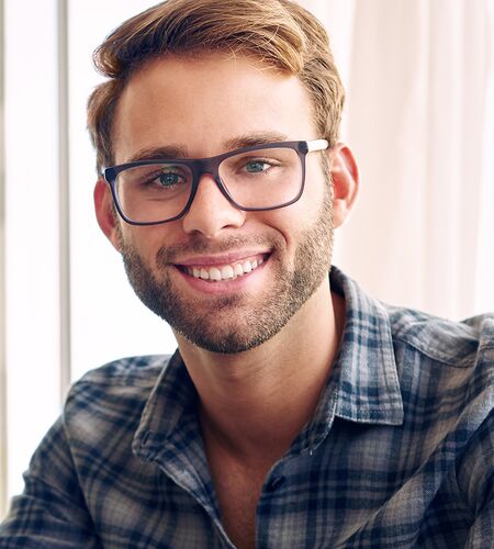Mann mit Brille mit Laptop schaut freundlich in die Kamera
