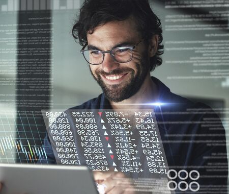 Person mit Brille hält Tablet, davor eingeblendete digitale Diagramme und Zahlen.