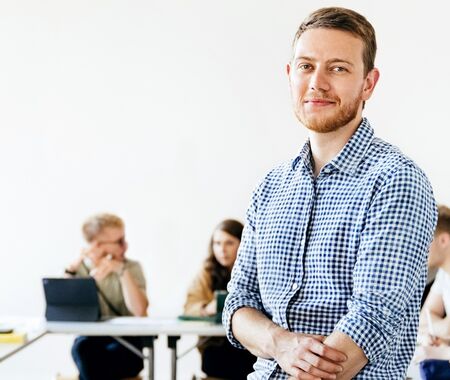Mann mittleren Alters steht inmitten einer Klasse