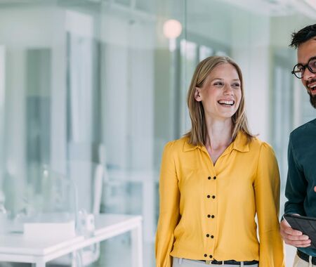 Kolleg*innen unterhalten sich gut gelaunt im Flur eines Büros