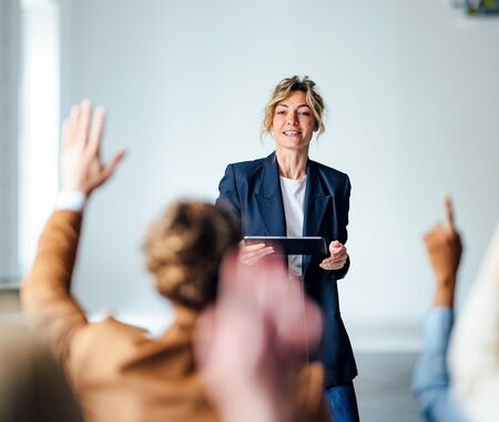 Lehrerin steht vor einer Gruppen von Menschen