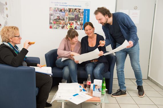 Fernstudium-Studierende im Pausenraum schauen sich Skizzen an