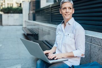 HFH Fernstudium Master Management im Gesundheitswesen Frau mit kurzen grauen Haaren tippt auf einem Laptop