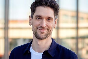 Mann vor gläserner Häuserfassade