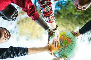 Kinderhände, die zusammen eine Weltkugel hochhalten