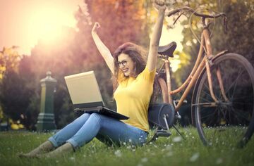 Eine Frau freut sich über eine Meldung auf Ihrem Laptop