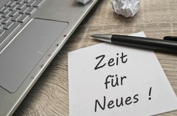 Laptop auf dem Tisch mit Notiz "Zeit für Neues!"