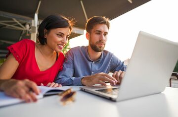 Frau und Mann an Tisch schauen gemeinsam in Laptop