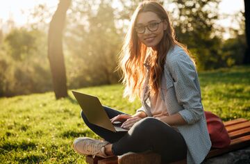 Junge Frau mit Notebook auf Wiese