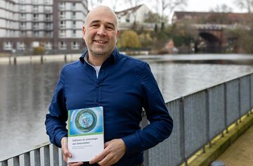 Portrait André Jäger mit Fachbuch in der Hand