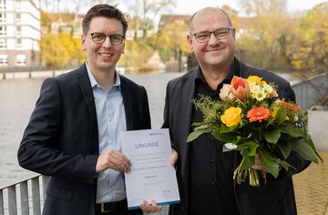 Prof. Dr. Lars Binckebanck überreicht Prof. Dr. Florian Oldenburg-Tietjen die Ernennungsurkunde und einen Blumenstrauß.