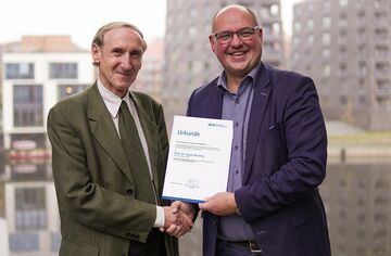 Portrait Prof. Muchna mit Prof. Binckebanck mit Urkunde vor Fernster