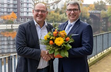 Prof. Binckebanck gratuliert Prof. Deckert mit Handschlag und Blumenstrauß