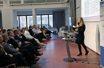 Speakerin steht vor Publikum und referiert