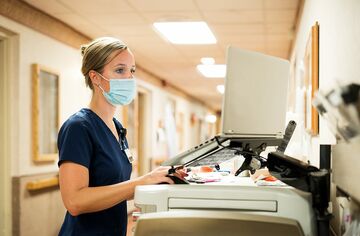 Krankenschwester mit Maske vor medizinischem Gerät