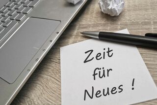 Laptop auf dem Tisch mit Notiz "Zeit für Neues!"