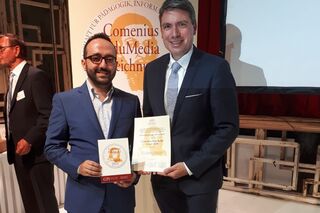 Othmane Kettani und Prof. Dr. Ronald Deckert mit Comenius-Urkunden vor Roll-up.