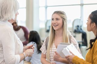Ältere Frau unterhält sich mit zwei Studentinnen.