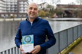 Portrait André Jäger mit Fachbuch in der Hand