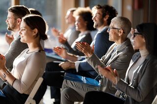 Publikum einer Konferenz sitzt und klatscht