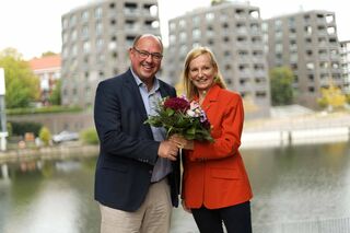 Prof. Dr. Lars Binckebanck überreicht Blumenstrauß an Prof. Dr. Irina Kummert am Osterbekkanal.