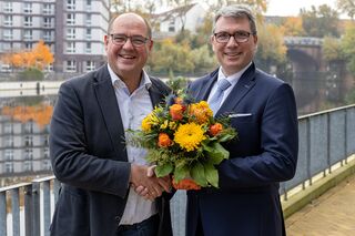 Prof. Binckebanck gratuliert Prof. Deckert mit Handschlag und Blumenstrauß