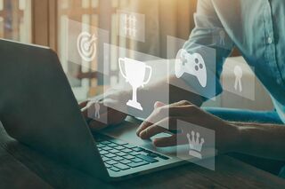 Laptop und Hände in Nahaufnahme mit eingeblendeten Spiele-Symbolen