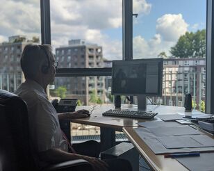 Mann sitzt am Fenster am PC und nimmt an Online-Konferenz teil