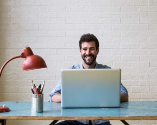 Mann sitzend an Tisch vor Notebook und Lampe