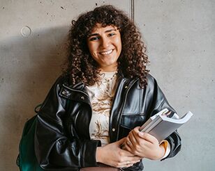 Portrait einer lachenden Studentin mit Studienunterlagen