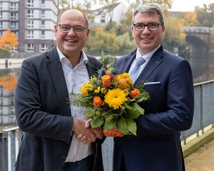 Prof. Binckebanck gratuliert Prof. Deckert mit Handschlag und Blumenstrauß