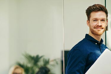 HFH Fernstudium Bachelor Wirtschaftspsychologie Mann in Hemd mit Laptop in der Hand