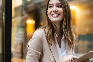 Junge Frau mit Blazer tippt auf einem iPad 