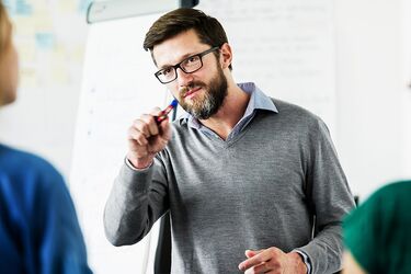 Dozent erklärt vor Schüler:innen einen Sachverhalt